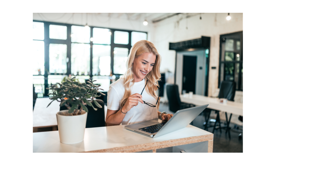 Smiling business owner reviewing financial reports on laptop, showcasing the benefits of good bookkeeping for business success and growth.